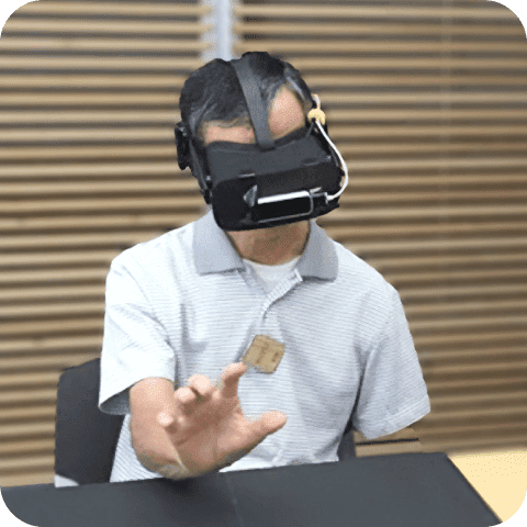 VRをつけて手で何かをつかもうとしてる人